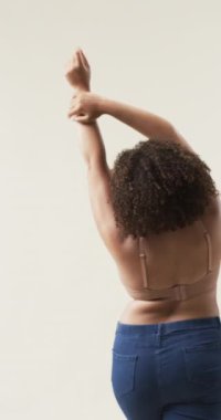 Dikey video: Kollarını esnetiyor, artı kot pantolon ve sutyen giyen kadın vücut pozitifliğini destekliyor. Güven, sağIık, gelişmişlik, uygunluk, kendini kabullenme, güçlenme