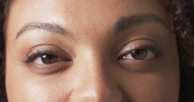 Çift cinsiyetli güzel, iri yarı, gözleri kapalı gülümseyen bir kadın. Parlak, iyi ışıklandırılmış stüdyo çekimlerinde vücut pozitifliğini ve kendini sevmeyi destekleyen, değiştirilmemiş