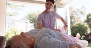 Fizyoterapist terapi seansında yaşlı kadına bacak egzersizinde yardımcı oluyor. Rehabilitasyon, fizyoterapi, sağlık, hasta, tedavi