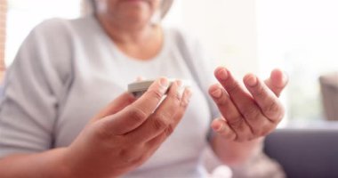 Üst düzey kadın evde glukometre kullanarak kan şekeri seviyesini ölçüyor. Diyabet, sağlık, izleme, glikoz, yaşlılık, tıbbi tedavi