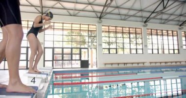 Erkek ve kadın yüzücüler kapalı havuz kenarındaki dalış bloklarında başlangıç pozisyonunda yarış için hazırlanıyorlar, kopyalama alanı. Rekabet, sporcular, spor, yüzme, odaklanma, yoğunluk