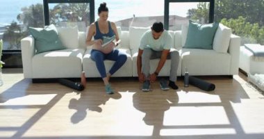 Erkek ayakkabı bağcıklarını bağlayıp egzersiz yapmaya hazırlanırken hamile kadın kanepede oturuyor. Hamilelik, çift, fitness, hazırlık, destek, aile