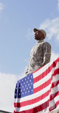 Dikey video: Selamlama, üniformalı asker Amerikan bayrağının yanında, vatanseverlik gösteriyor. Ordu, onur, adanmışlık, saygı, ABD, silahlı kuvvetler