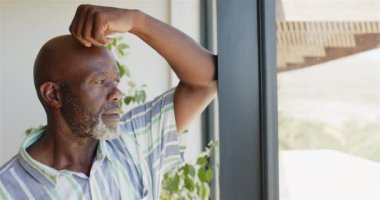 Pencereden dışarı bakan, düşünceli, Afro-Amerikan bir adam içerideki hayatı düşünüyor, kopyalama uzayı. Düşünce, içgözlem, yalnızlık, düşünceli, yalnız, orta yaşlı