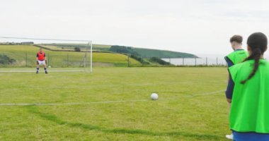 Erkek ve bayan futbolcular, bir oyuncu kaleye ateş ediyor ve sahada sayı yapıyor. spor, yaşam tarzı, takım çalışması, futbol ve etkinlik.