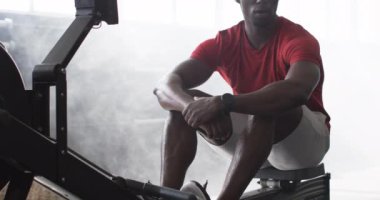 Yoğun egzersizden sonra dinleniyor, spor salonunda egzersiz makinesinde oturan bir adam. Fitness, atlet, antrenman, iyileşme