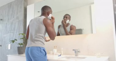 Traş kremi sürüyorum, Afro-Amerikalı bir adam banyo aynasına bakıyor, rutin tımar. Sabah rutini, hijyen, kişisel bakım, yansıma, cilt bakımı, değişmemiş, yavaş çekim
