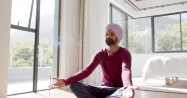 Evde meditasyon yapan, türbanlı Hintli adam tütsüyle bilinç egzersizi yapıyor. Sağlık, meditasyon, maneviyat, rahatlama, sakinlik, huzur.