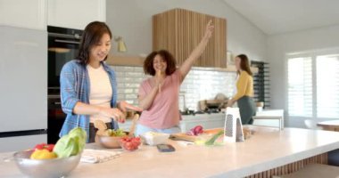 Mutfakta birlikte yemek pişirirken, üç farklı kadın arkadaş yemek hazırlayıp dans etmekten zevk alıyor. Arkadaşlık, eğlence, yemek hazırlığı, birliktelik, keyif, aşçılık