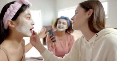 Yüz maskesi takmak, cilt bakımını seven üç farklı kadın arkadaş. Sağlık, güzellik, arkadaşlar, şımartma, kendine bakım, rahatlama.