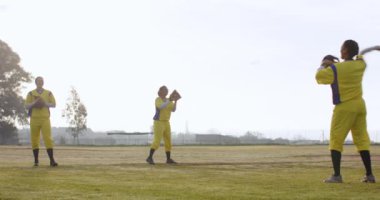 Çok ırklı bayan beyzbol oyuncuları bir sahada topu yakalayıp birbirlerine atıyorlar. Spor, etkinlik, takım çalışması, antrenman ve beyzbol.