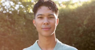 Açık havada gülümseyen genç bir adam, güneşli bir günün keyfini çıkarıyor. Mutluluk, güneş ışığı, neşe, yaşam tarzı, boş zaman, tasasız