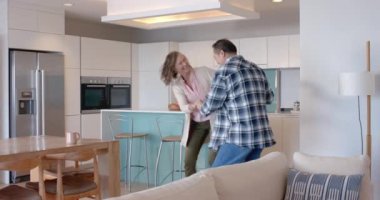 Birlikte dans ediyorlar, son sınıf çifti evde modern mutfakta eğleniyorlar. Aile, birliktelik, yaşam tarzı, emeklilik, aşk, mutluluk, değişmemiş, yavaş çekim