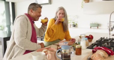 Kahvaltı yapıyorlar, çok kültürlü yaşlı çiftler modern mutfakta, evde sabah yemeğinin tadını çıkarıyorlar. Beraberlik, ev, yaşam tarzı, yemek