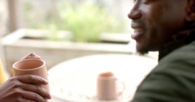 Elinde fincanla, gülümseyen ve sıcak içecekten hoşlanan Afrikalı Amerikalı bir kadın. Rahatlama, rahatlık, mutluluk, rahatlık, ev içi, içecek.