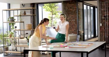 Modern ofiste işbirliği yapan kadınlar dizüstü bilgisayar ve kahve fincanı ile fikirleri tartışıyor. İşbirliği, takım çalışması, beyin fırtınası, iş, teknoloji, toplantı