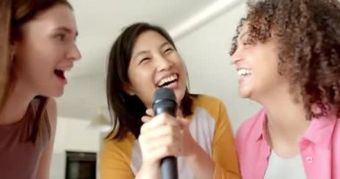 Birlikte şarkı söylemek, evde karaoke yapan üç kadın arkadaş, mikrofon tutmak. Eğlence, müzik, arkadaşlar, eğlence, parti, eğlence