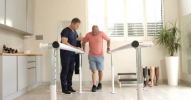 Paralel parmaklıklarda yürüyen protez bacaklı bir adama yardım eden terapist. Rehabilitasyon, fizyoterapi, sağlık, sağlık, iyileşme, protez