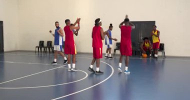 Çok ırklı erkek basketbol oyuncuları kutlama yapıyor, el çırpıyor ve spor salonunda birbirlerine sokuluyorlar. spor, yaşam tarzı ve etkinlik.