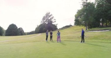 Golf oyuncuları birlikte golf oynuyorlar, golf sahasında golf sopasıyla topa vuruyorlar. spor, etkinlik ve golf.