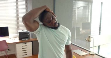 Boyun kaslarını esneten, ofiste dizüstü bilgisayarla rahatlayan bir adam. Sağlık, rahatlama, uzaktan çalışma, serbest çalışma, değişmemiş, yaşam tarzı.