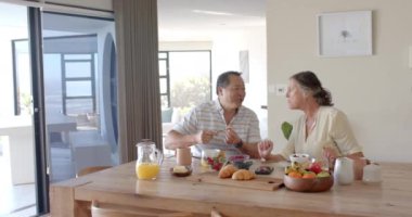 Kahvaltı yapıyorlar, son sınıf çifti yemek masasında taze meyve ve kruvasanın tadını çıkarıyorlar. Sabah, yemek, sağlıklı beslenme, birliktelik, yaşam tarzı, içeride, değişmemiş, yavaş çekim