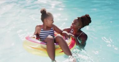 Bilardoda oynuyorlar, anne ve kızı şişme yüzükle yaz gününün tadını çıkarıyorlar. Afro-Amerikan ailesi, yüzme, eğlence, boş zaman, açık hava