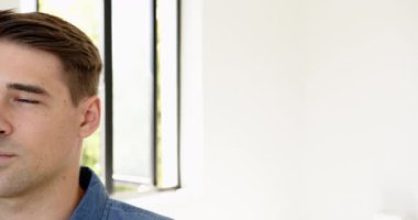 Parlak bir odada, büyük pencereli, rahat gömlekli, gülümseyen adam, evinde, fotokopi uzayı. Mutlu, kapalı, yaşam tarzı, doğal ışık, pozitif, modern