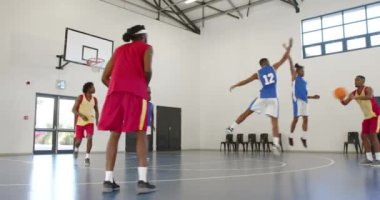 Basketbol oynayan, pas veren ve spor salonunda basketbol oynayan çok ırklı erkek basketbolcular. spor, yaşam tarzı ve etkinlik.