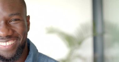 Gülümseyen Afro-Amerikan adam evde dinleniyor, boş zamanların tadını çıkarıyor, fotokopi çekiyor. Rahatlama, mutluluk, kapalı alan, yaşam tarzı, değişmemiş, yaşam tarzı