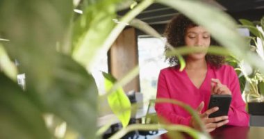 Akıllı telefonu tutan, pembe bluzlu bir kadın modern ofis yerinde duruyor. İş, teknoloji, işyeri, şirket, profesyonel, yönetici