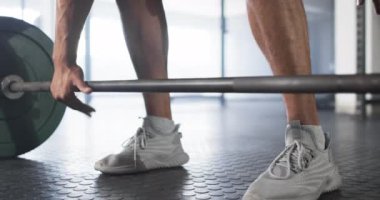 Halteri kaldıran, spor salonunda spor ayakkabı giyen bir adam. Fitness, egzersiz, egzersiz, güç, eğitim, teknoloji