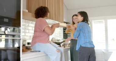 Modern mutfakta içki içip sohbet eden üç kadın arkadaş. Arkadaşlık, birliktelik, sohbet, mutluluk, kapalı alan, yaşam tarzı