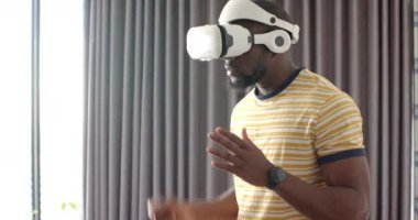 VR kulaklık takan bir adam evde sanal gerçeklik deneyiminin tadını çıkarıyor. Teknoloji, oyun, eğlence, değiştirilmemiş yaşam tarzı.
