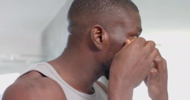 Göz altı bantları uygulayan Afro-Amerikalı bir adam ev spa 'sında cilt bakımını seviyor. Kişisel bakım, şımartma, tımar, sağIık, rahatlama, değiştirilmemiş, yavaş çekim