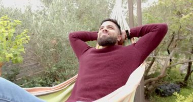 Hamakta dinlenen, arka bahçede boş zamanların tadını çıkaran bir adam. Sağlık, rahatlama, huzur, yaşam tarzı, yaz, izin günü.