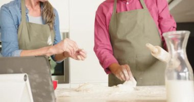 Birlikte yemek yapmak, çok ırklı üst düzey çiftler hamur yoğurmak ve evde, mutfakta tablet kullanmak. birliktelik, aşçılık, teknoloji, takım çalışması, dijital, malzemeler