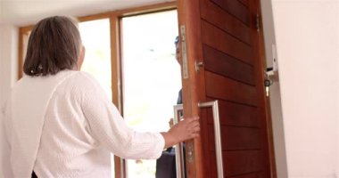 Steteskopla gülümseyen erkek fizyoterapist yaşlı bayanı karşılıyor. Sağlık, fizyoterapi, ev ziyareti, güven, yaşlı bakımı, tıbbi bakım