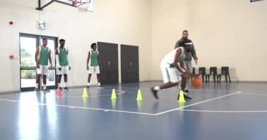 Basketbol oynayan çok ırklı erkek basketbolcular spor salonunda koçla külahlardan kaçınıyorlar. spor, yaşam tarzı ve etkinlik.