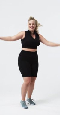 Dikey video: Neşeyle dans etmek, artı beden ölçülerinde bir kadın vücut pozitifliğini kutluyor. Fitness, aktif giyim, kutlama, bayan sporcu, motivasyon, güçlendirme
