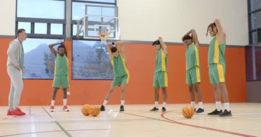 Spor salonunda koç olan, kollarını ve bacaklarını esneten çok ırklı erkek basketbol oyuncuları. spor, yaşam tarzı ve etkinlik.
