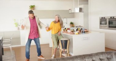 Birlikte dans ediyorlar, mutlu çok ırklı son sınıf çifti modern ev yemeği alanında eğleniyorlar. Mutluluk, kutlama, yaşam tarzı, içeride, dans, birliktelik