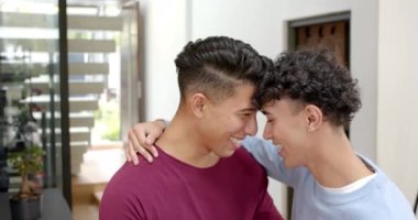 Gülümseyen, çok ırklı eşcinsel çift evde şefkatli anları kucaklıyor ve eğleniyor. LGBTQ, aşk, ilişki, mutluluk, mahrem, kapalı alan