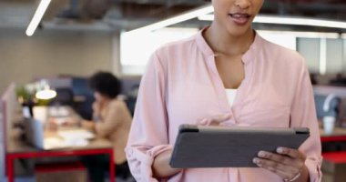 Modern ofiste tablet kullanan Afrikalı Amerikalı bir kadın, meslektaşlarıyla çalışma alanı açıyor. Girişimci olarak, insanların yoğun bir atmosfer yaratmasıyla gelişigüzel, değişmeden modern bir altyapı başlatın.