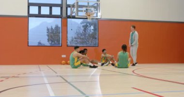 Beden eğitimi koçu olan çok ırklı erkek basketbol oyuncuları bir araya gelip koçu dinliyorlar. spor, yaşam tarzı ve etkinlik.
