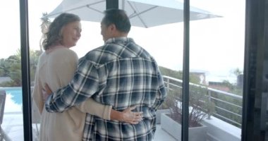 Tatil evi manzarasına bakan yaşlı çift kucaklaşıyorlar. Emeklilik, rahatlama, birliktelik, aşk, mutluluk, açık hava, değişmemiş, yavaş çekim