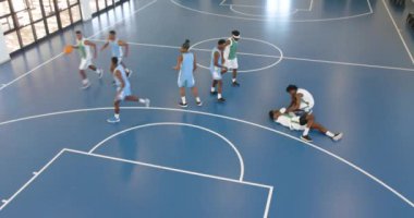 Basketbol oynayan çok ırklı erkek basketbolcular, bir oyuncu diğerine spor salonunda yardım ediyor. spor, yaşam tarzı ve etkinlik.