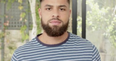 Sakallı, çizgili tişörtlü, dışarıda duran gülümseyen genç adam. Portre, günlük, yaşam tarzı, neşeli, mutluluk, moda