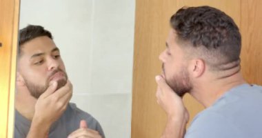 Sakallı, fırça kullanan ve banyoda aynaya bakan bir adam. Hijyen, fırçalama, kişisel bakım, kişisel bakım, günlük rutin, yansıma