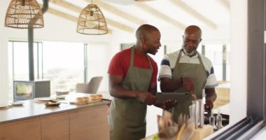 Mutfakta birlikte yemek pişirmek, baba oğul yemek tarifi için tablet kullanmak. Aile, teknoloji, bağlılık, babalık.